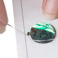 Needle beginning to bead around a cabochon